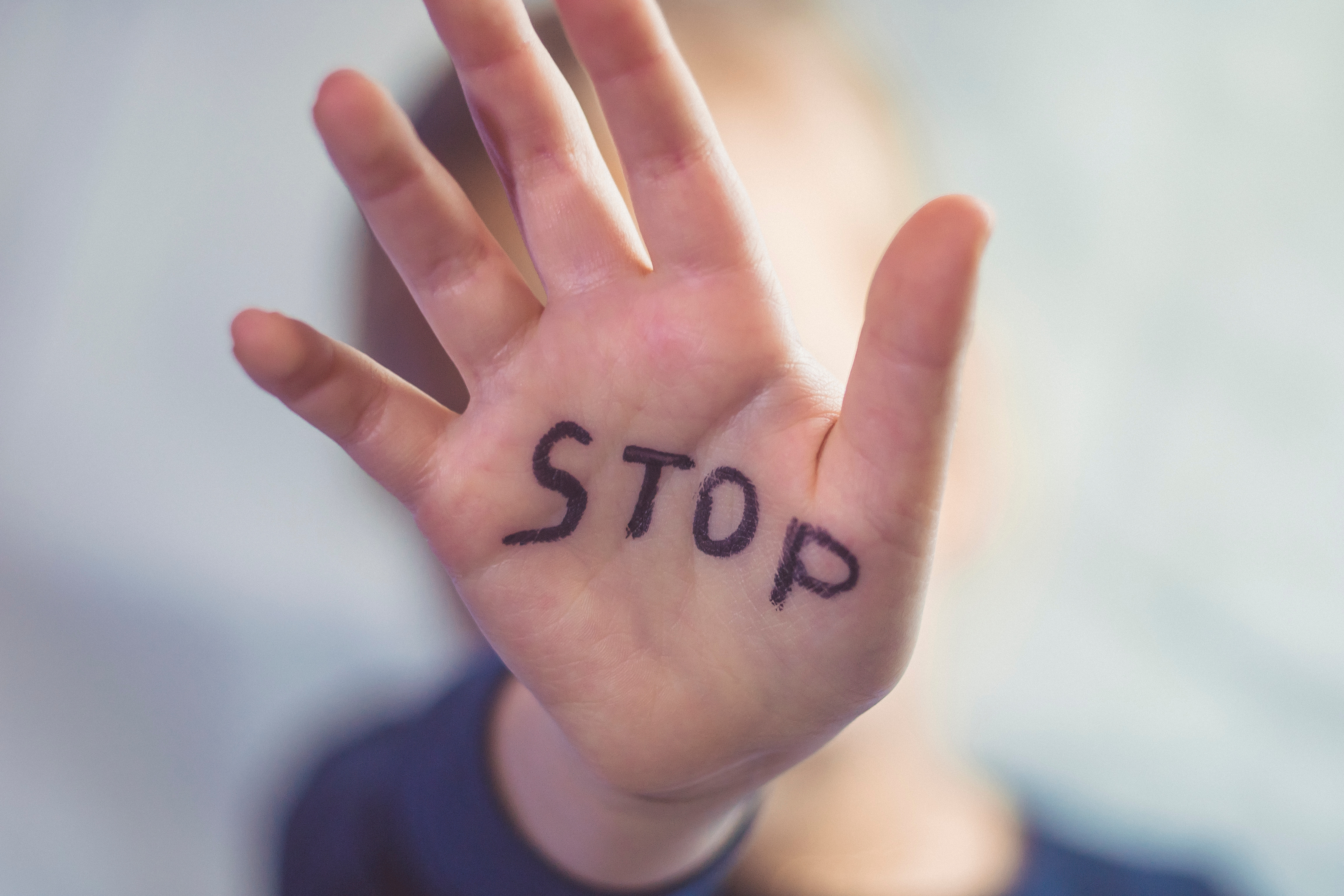 Foto von Handfläche, auf der in schwarzer Schrift "Stop" steht