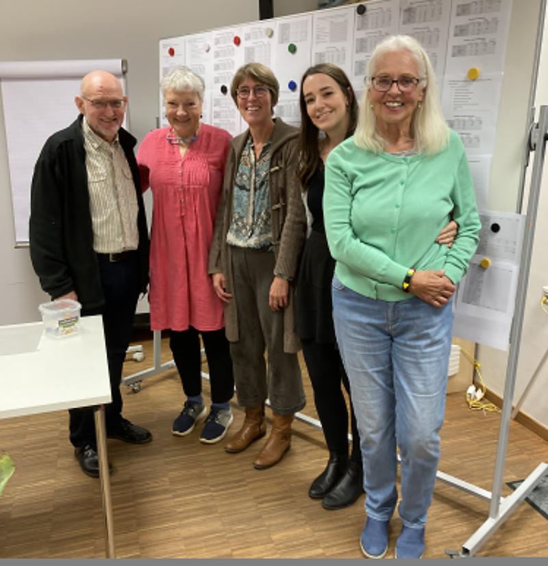 fünf Personen vor einer Pinnwand mit vielen Ausdrucken